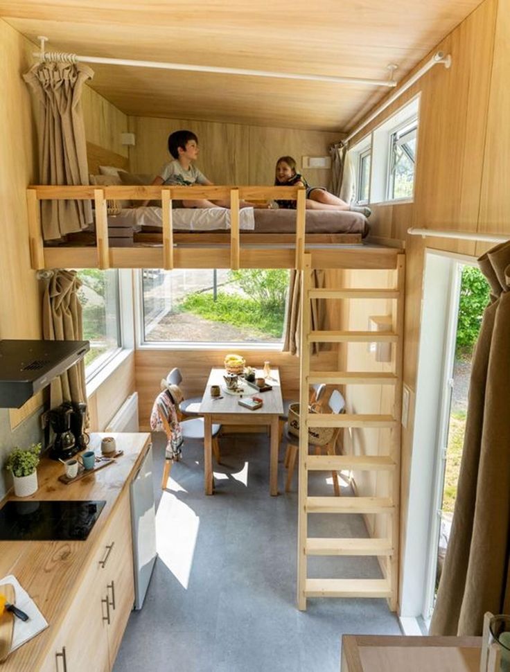 two people are sitting on bunk beds in a tiny house with stairs to the second floor