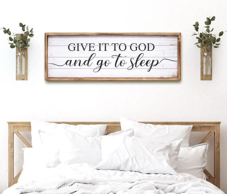 a bed with white sheets and pillows in front of a wooden sign that says give it to god and go to sleep