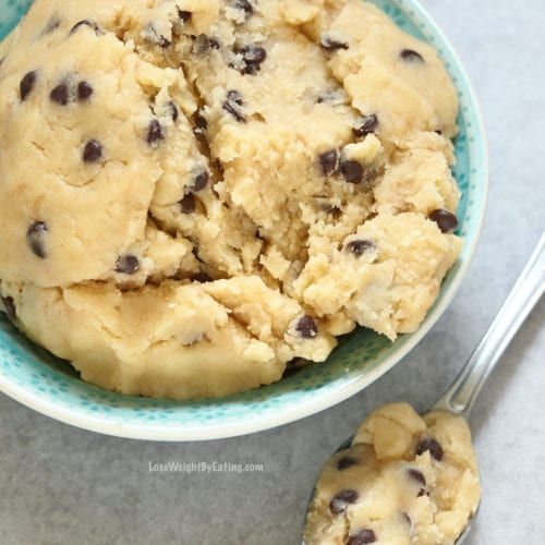 a bowl filled with chocolate chip cookie dough next to a spoon