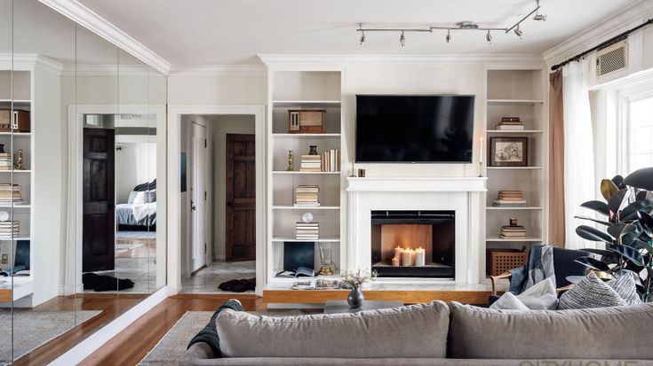 a living room with a fire place and white furniture