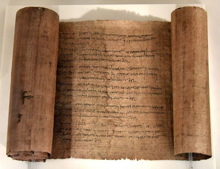 an old scroll with writing on it in a museum display case next to a white wall