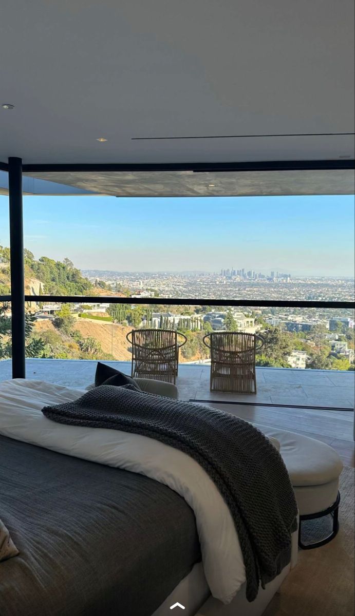 a large bed sitting in the middle of a bedroom next to a tall glass wall