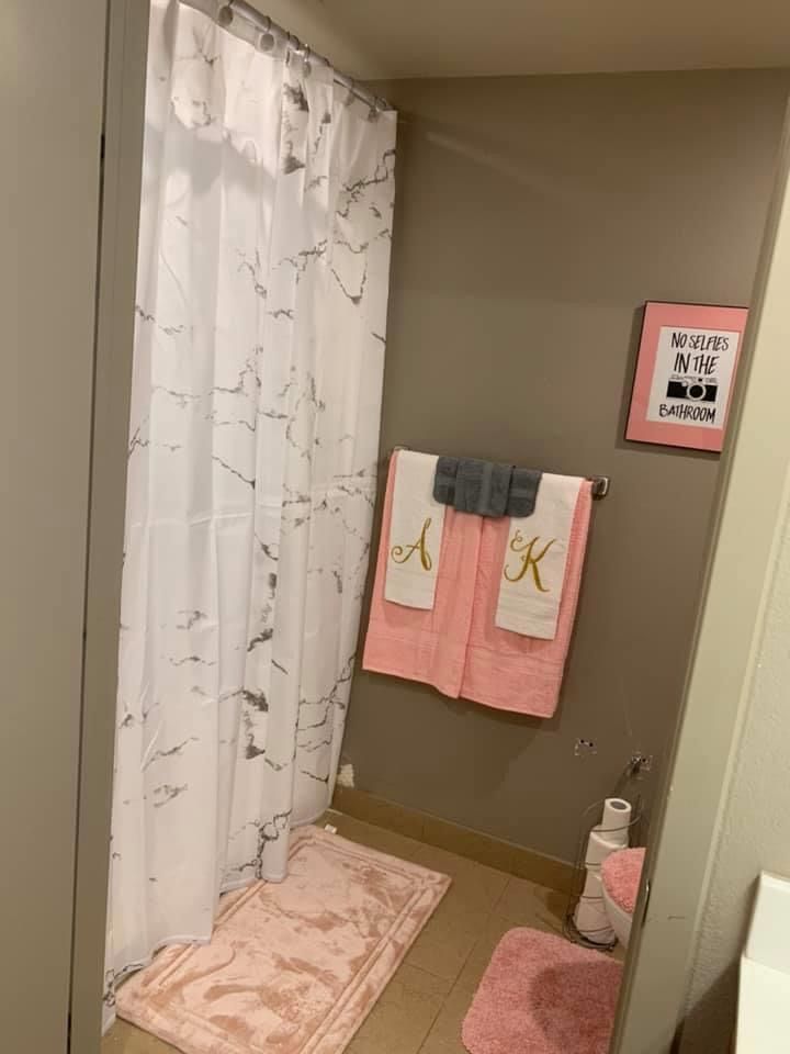 a bathroom with two towels hanging on the wall and pink rugs next to it