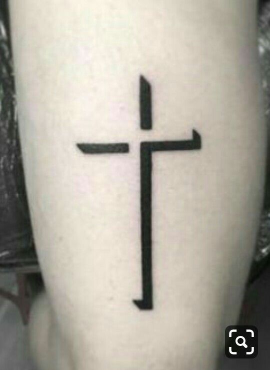 a black and white photo of a cross on someone's leg with the word jesus written in it