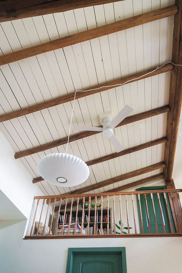 a ceiling fan is hanging from the rafters above a balcony with green doors and railings