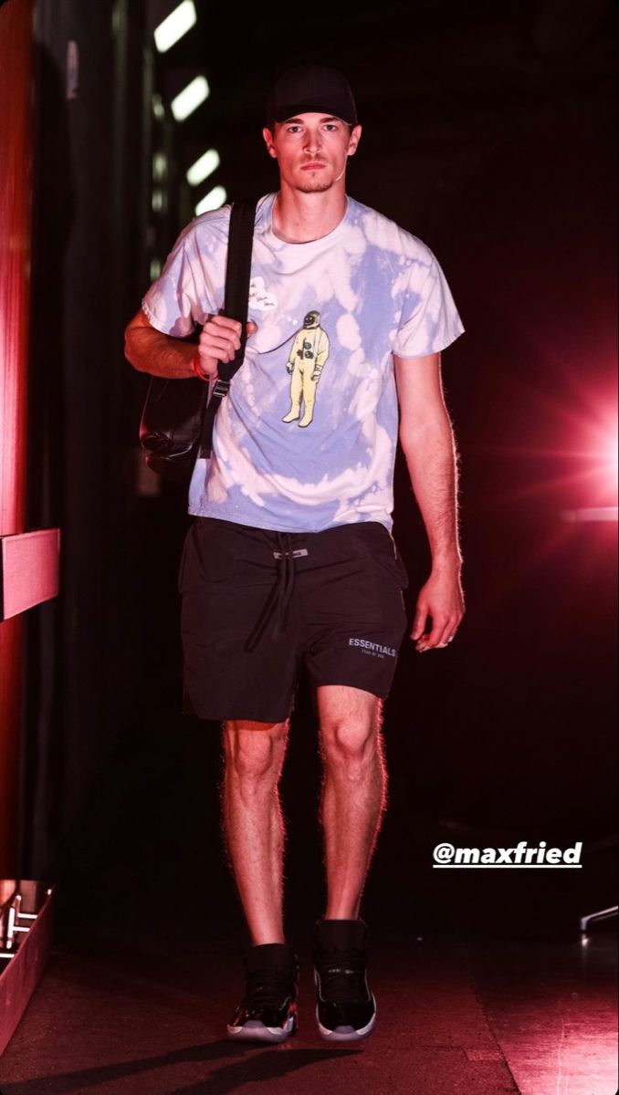 a young man is walking down the runway wearing shorts and a t - shirt with an image on it