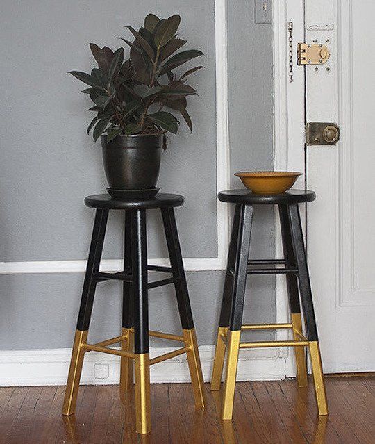 two black and gold stools next to each other in front of a white door