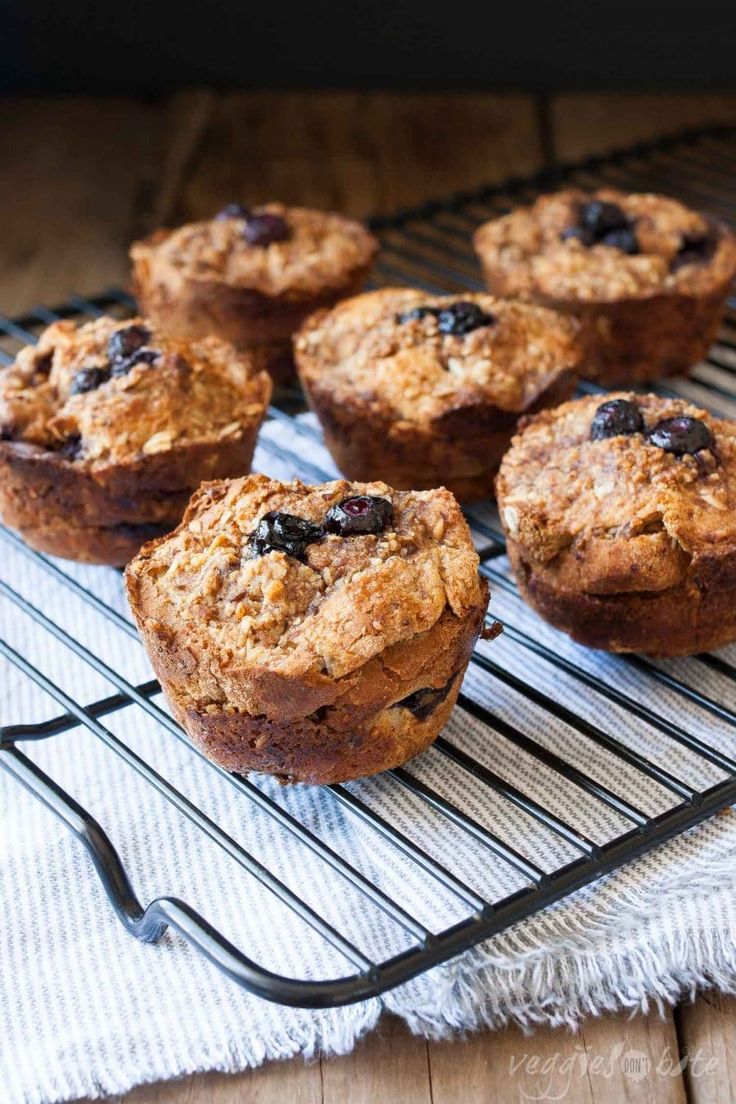 muffins cooling on a wire rack with blueberries in the middle and oatmeal topping