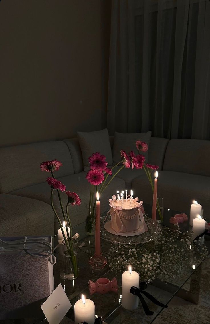 a living room filled with lots of candles next to a table topped with a cake