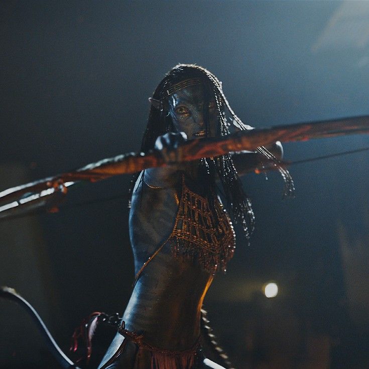 a woman dressed in native american clothing holding a bow and arrow while standing on stage