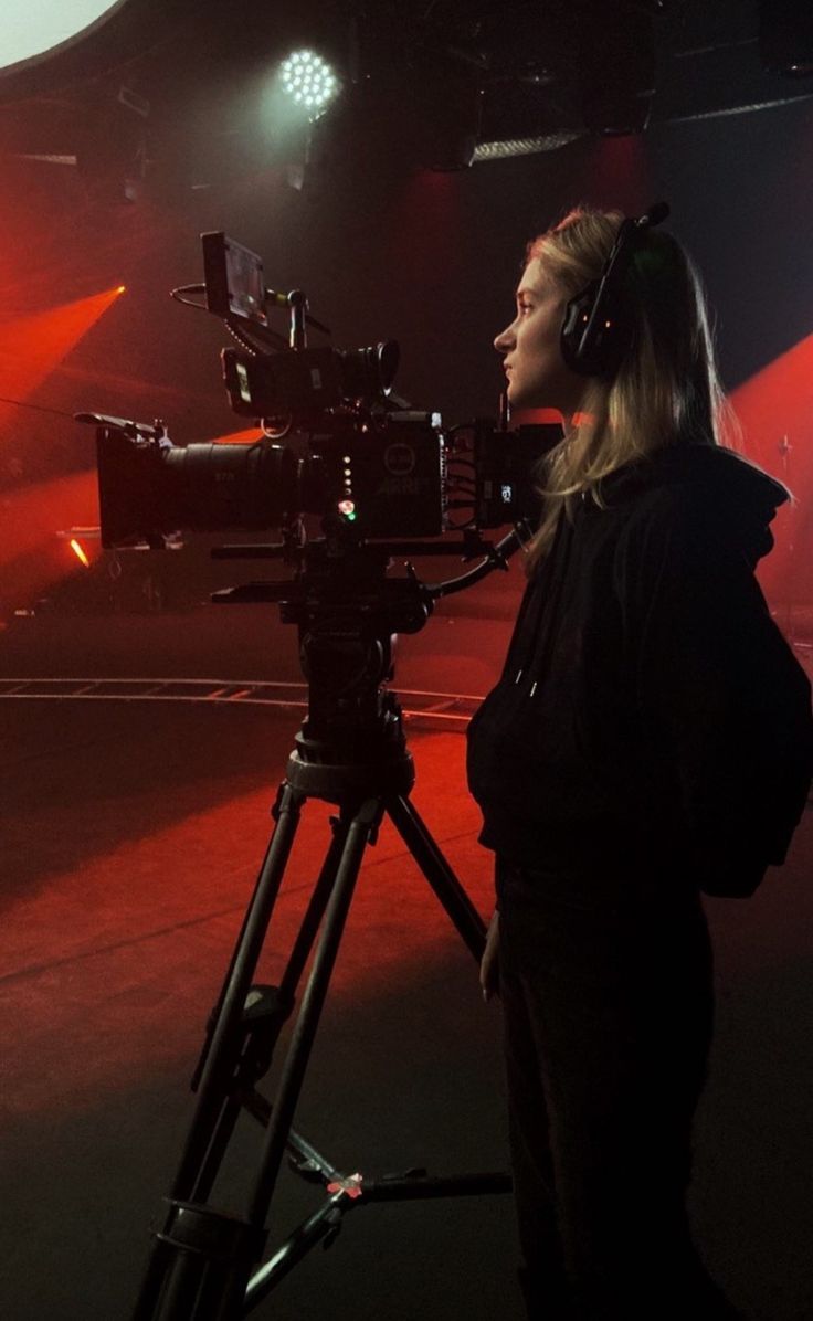 a woman standing in front of a camera on top of a tripod with headphones