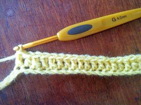 a yellow crochet hook is next to a knitting needle