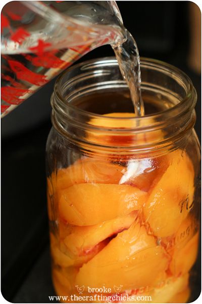 a glass jar filled with sliced peaches and water pouring from a pitcher into it