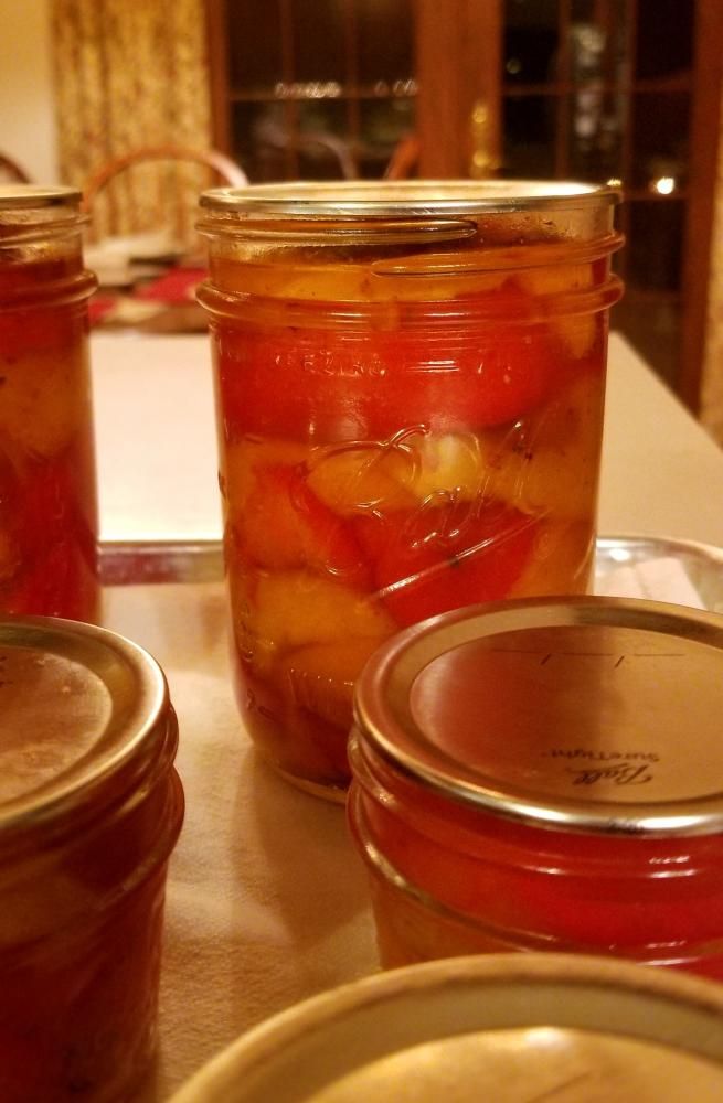 jars filled with pickled fruit sitting on top of a table