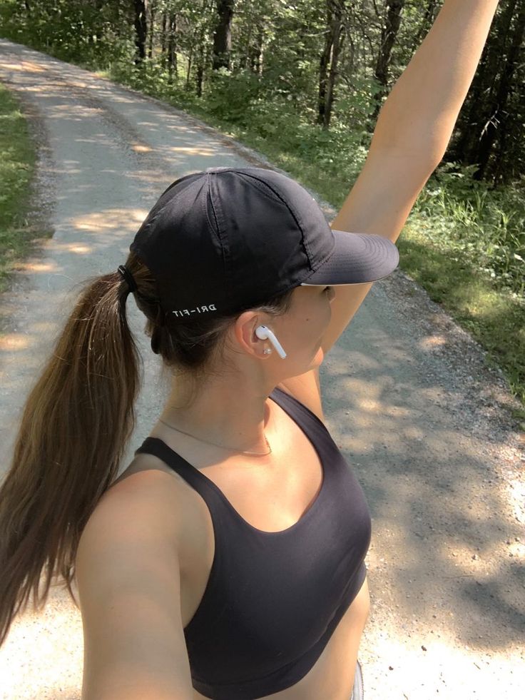 a woman is holding her arm up in the air while standing on a dirt road