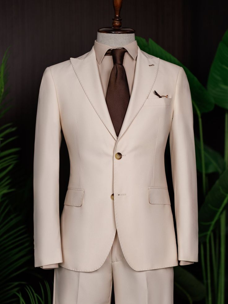 Color: beige Material: 73% polyester, 23% viscose, 4% elastane Suit includes blazer, waistcoat, & trousers Single-breasted suit (2-button blazer) Lapel type: peak lapels Jacket interior lining option: fully-lined Jacket vent: double vent Fitting: modern-fit Care instructions: dry clean only Machine washable: no Slim Fit Single-breasted Three-piece Suit, Beige Suits With Welt Pockets For Business Casual, Beige Double Breasted Suit For Business Casual, Beige Business Casual Suits With Welt Pockets, Cream Single Breasted Blazer With Notch Lapel, Tailored Single-breasted Three-piece Suit, Beige Tuxedo Set For Business, Slim Fit Single Breasted Three-piece Suit For Business Casual, Beige Single Breasted Suit Set For Work