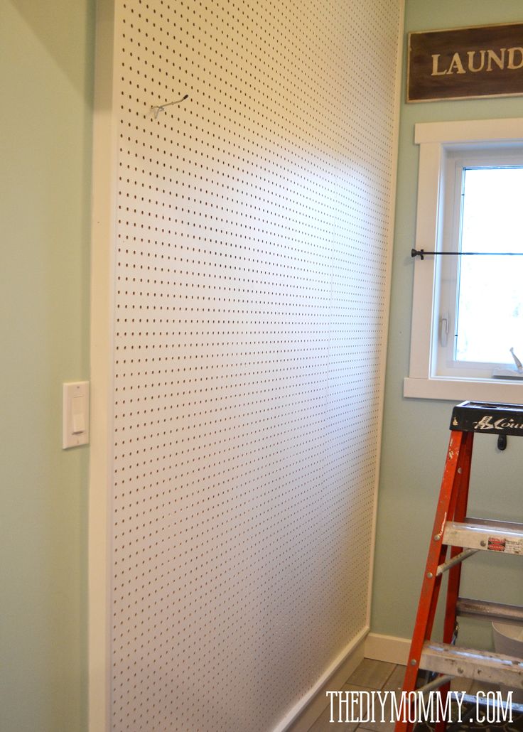 a ladder is in front of a white wall with holes on it and a window