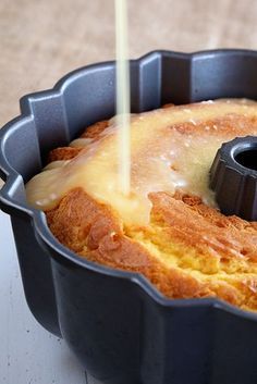 a bundt cake in a black pan being drizzled with icing