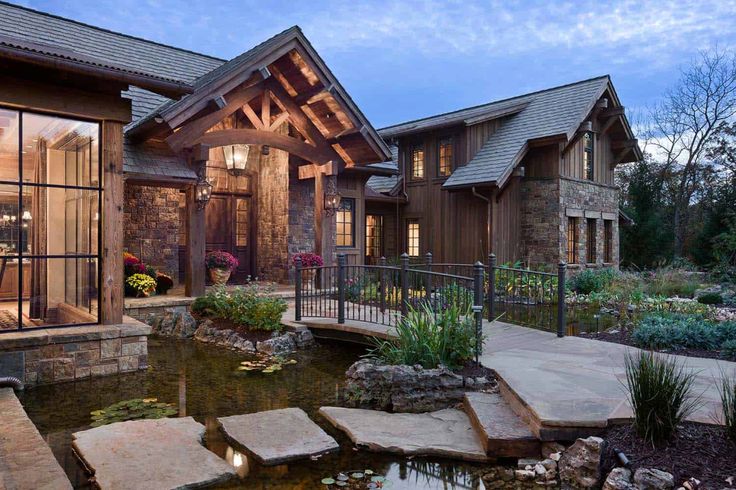 a house with a pond in front of it and stone steps leading up to the porch