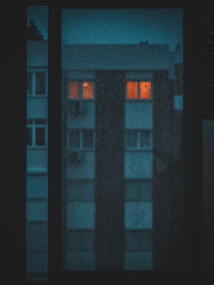 two windows with red light shining through them in the dark, and one window is closed