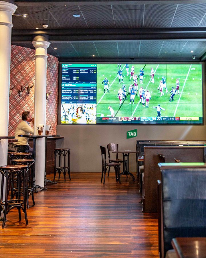 a man sitting at a table in front of a big screen tv on the wall