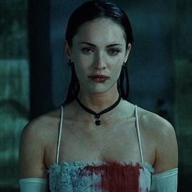 a woman with long hair wearing a red and white dress in a dark room, staring at the camera