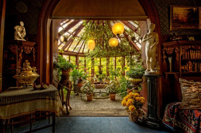 an open door leading into a garden with potted plants and flowers on the table