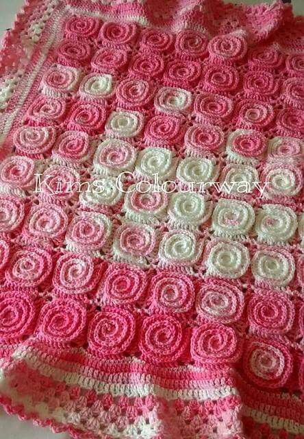 a pink and white crocheted blanket sitting on top of a table