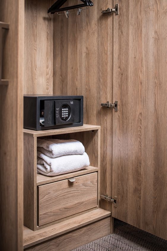 a microwave sitting on top of a wooden shelf next to towels and other items in a closet