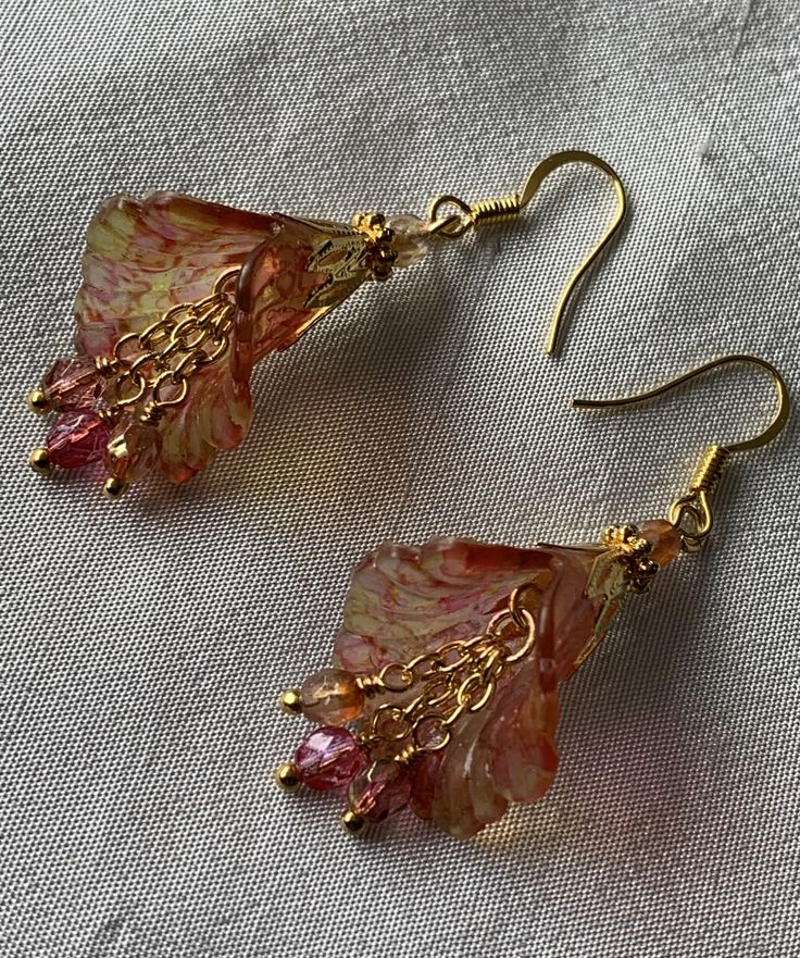 the earrings are made from glass and gold plated wire, with pink flowers on them