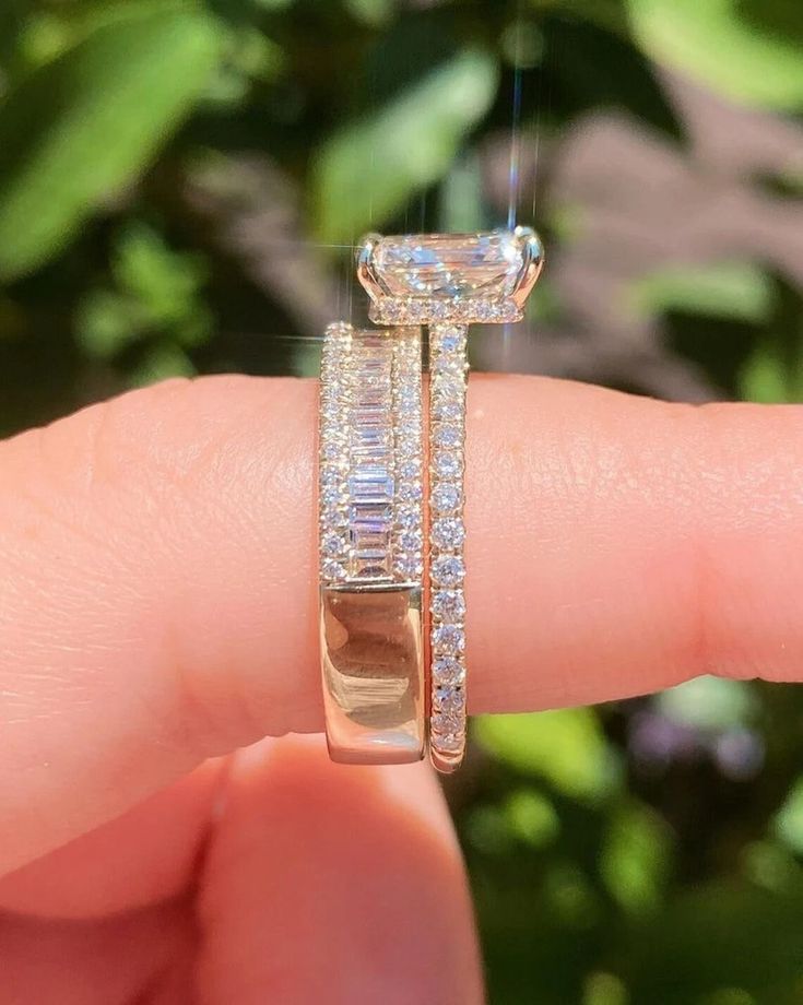 a woman's hand is holding an engagement ring with two rows of diamonds on it