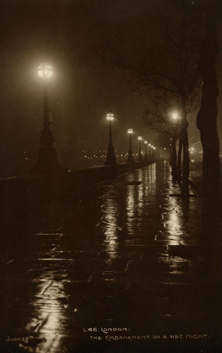 an old black and white photo of street lights on a rainy night in the city