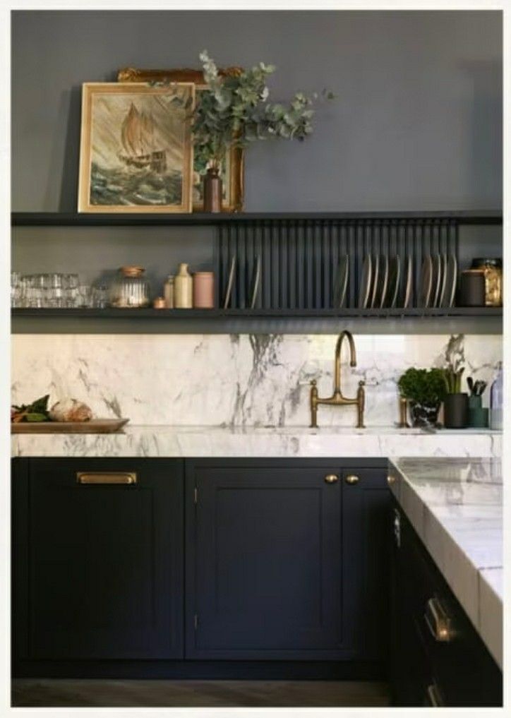 a kitchen with marble counter tops and black cabinets, along with open shelving above the sink