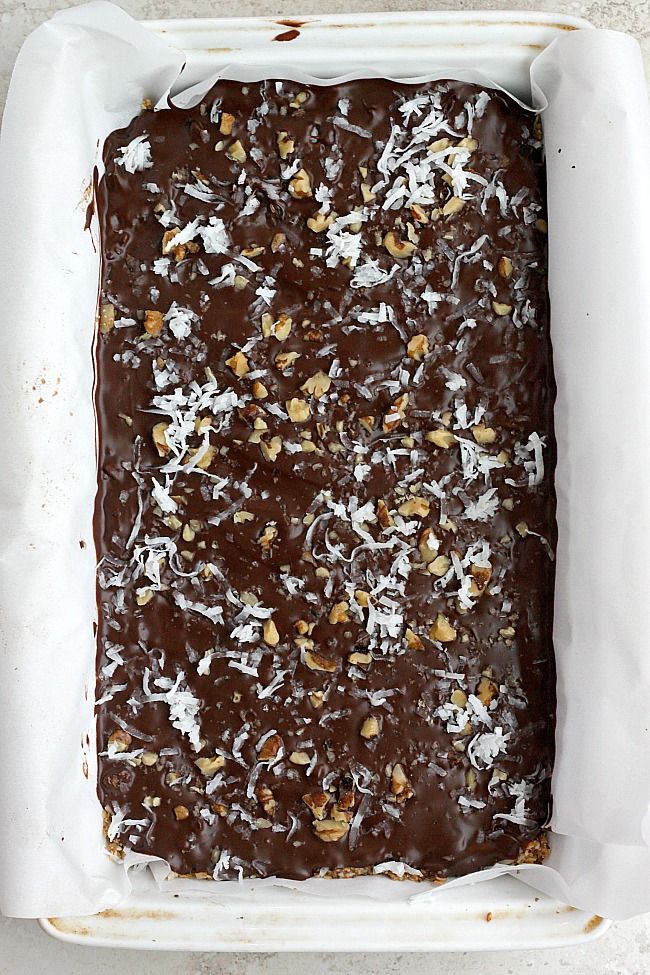 a square chocolate cake with nuts on top in a baking pan, ready to be baked