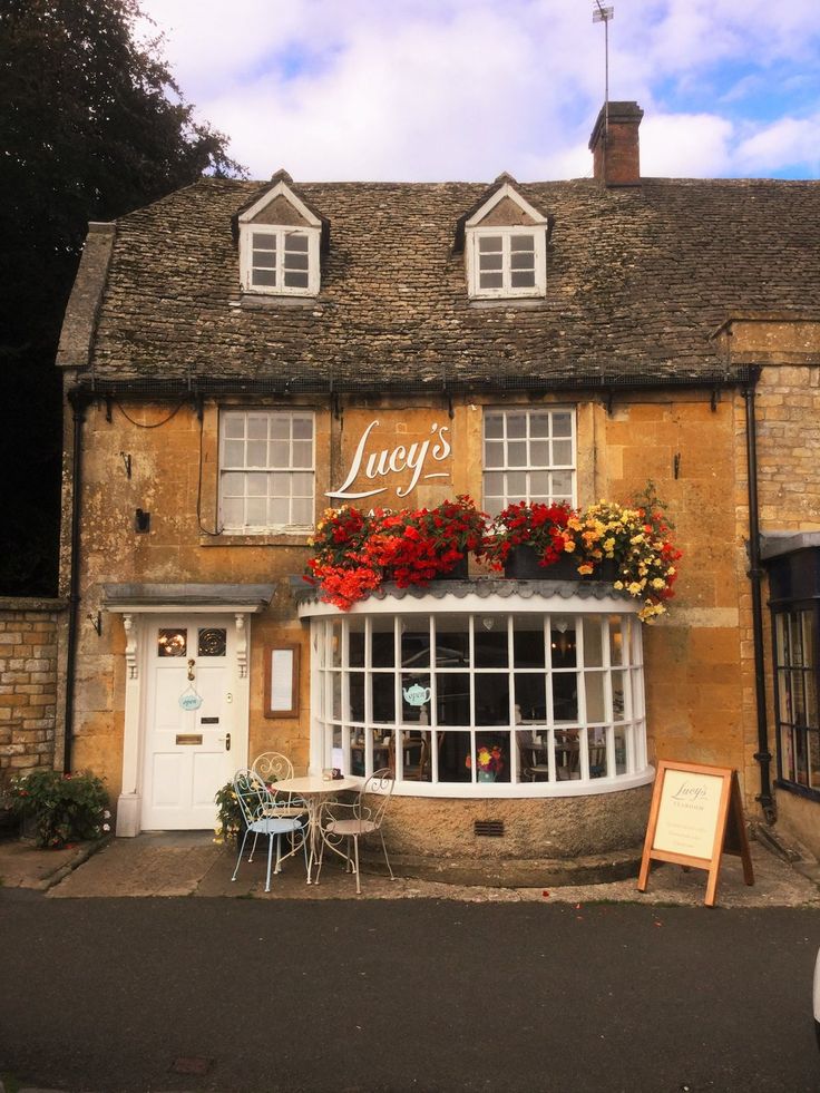 an old building with flowers on the windows and tables in front of it that says leroy's