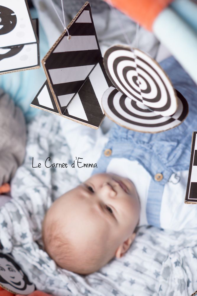 a baby laying on top of a bed next to some kites hanging from the ceiling