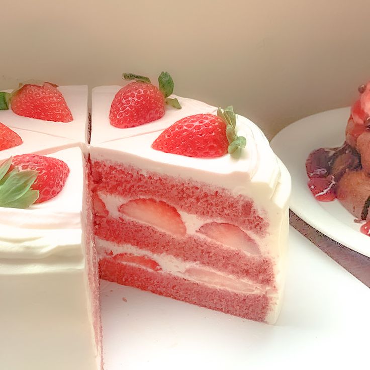 a slice of strawberry cake with white frosting and fresh strawberries on the top