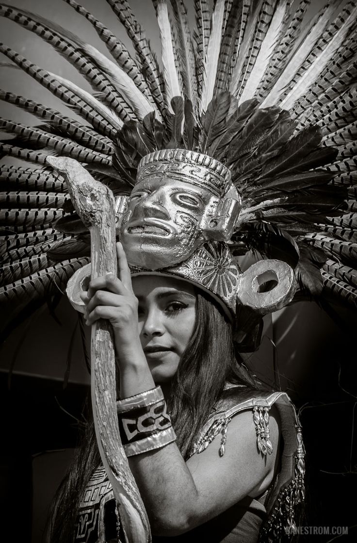 a woman wearing an elaborate headdress and holding a large snake in her hand