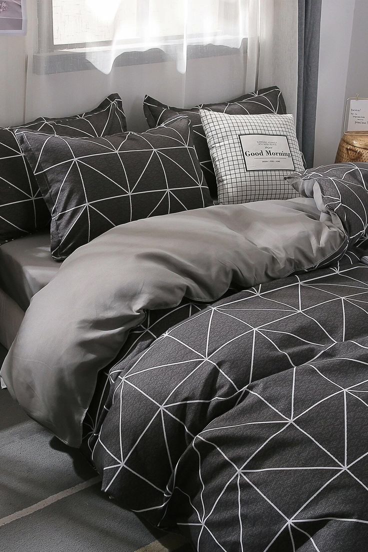 a bed with black and white comforters in front of a window