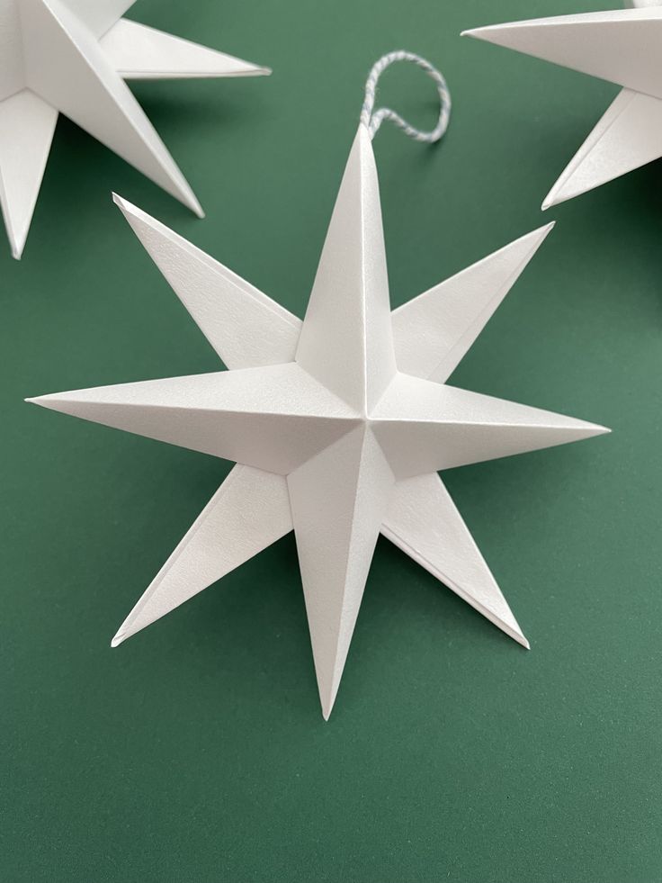 three white origami stars on a green surface