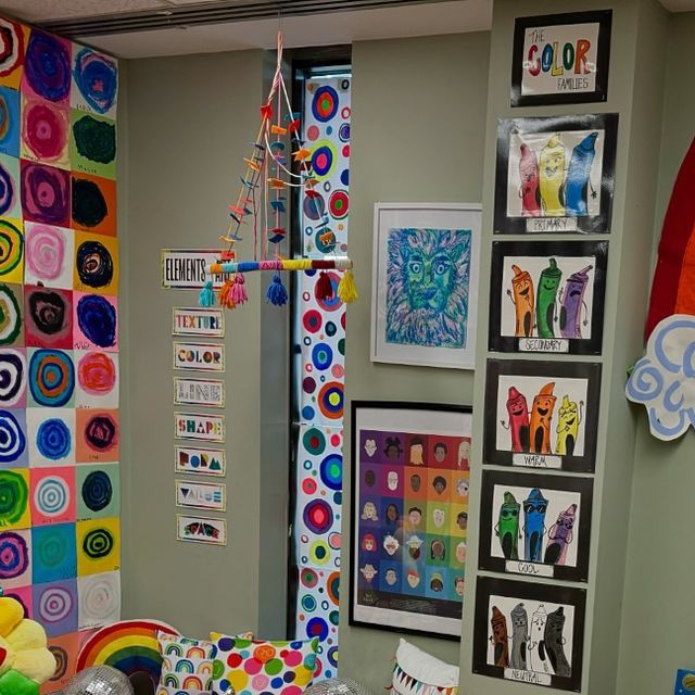 an office decorated with lots of colorful art and pictures on the wall, along with balloons