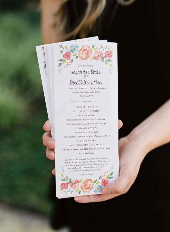 a close up of a person holding a wedding program in their hand with flowers on it