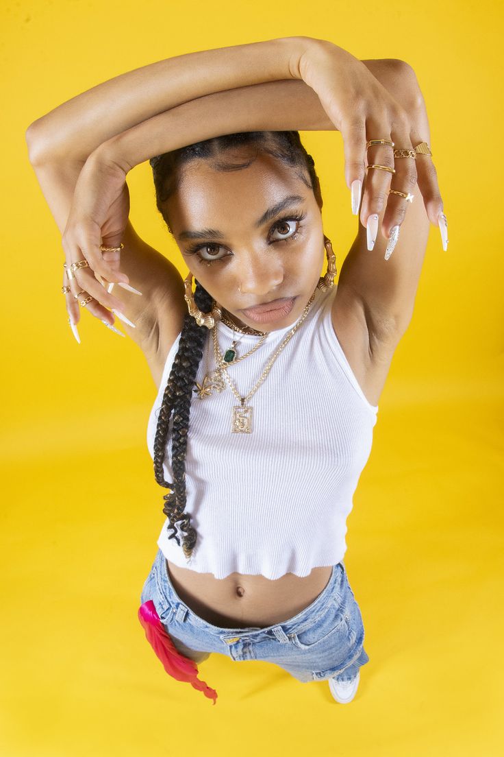 a young woman with braids on her head posing for a photo in front of a yellow background