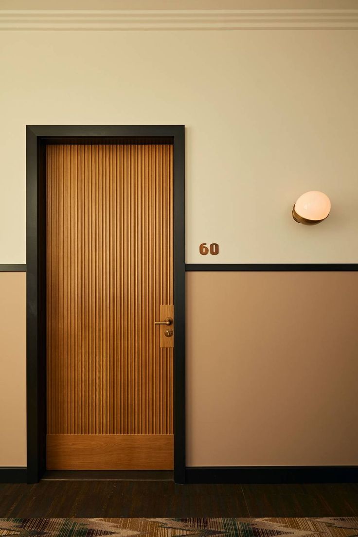 an empty room with a wooden door and two lamps on the wall next to it