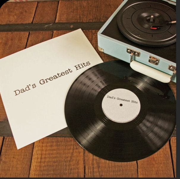 a record player sitting next to a paper with the words dad's greatest hits on it