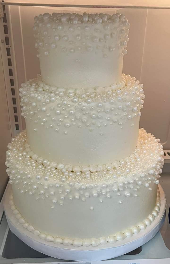 a three tiered white cake with pearls on it