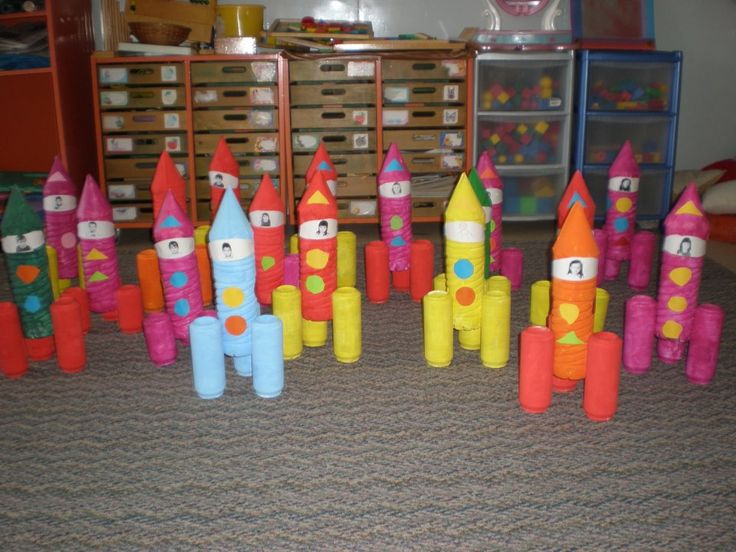 there are many colorful toy rockets on the floor in front of some shelves and bins