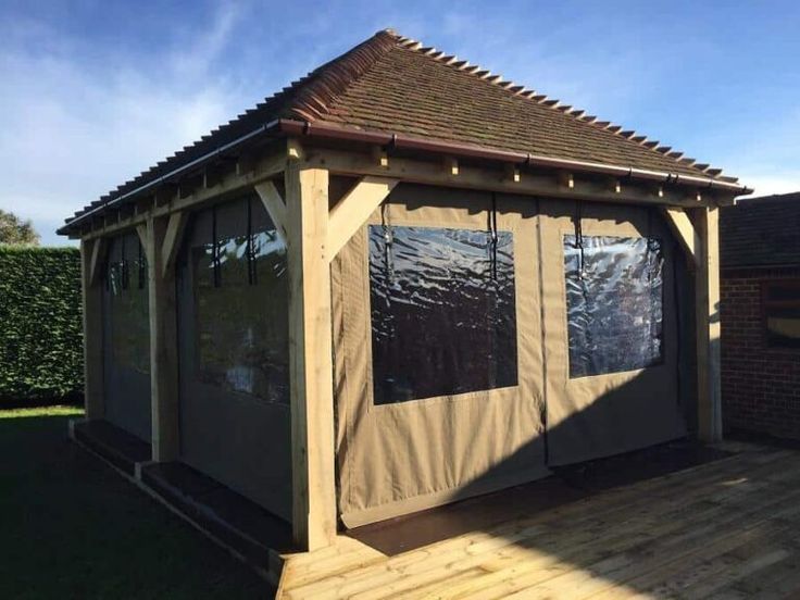 a covered gazebo sitting on top of a wooden deck next to a green field