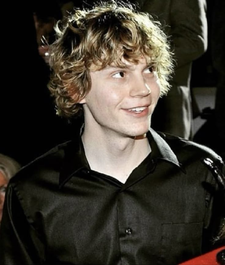 a young man with curly hair is smiling