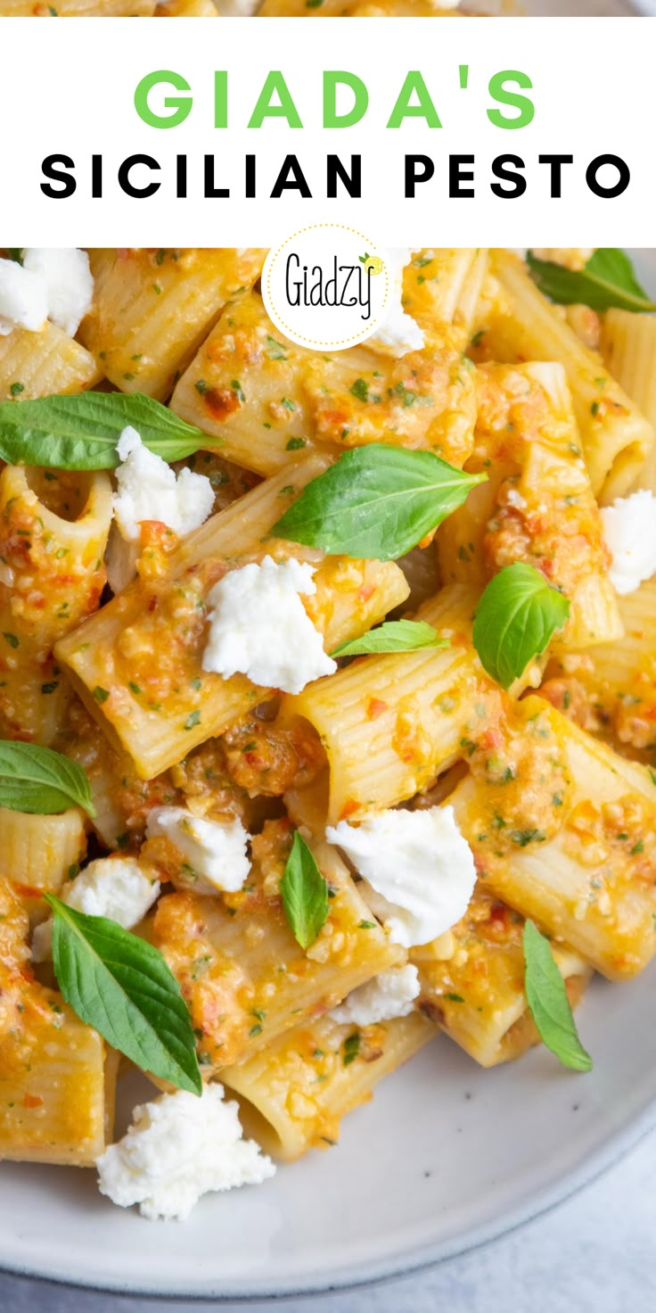 a white plate topped with pasta covered in fettuccine, cheese and basil